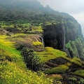 Monsoon trek to Naneghat in Maharashtra with lush green hills, mist-covered trails, and adventurous hikers exploring the scenic Western Ghats.