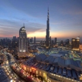 Panoramic view of Downtown Dubai featuring the Burj Khalifa, luxury hotels, modern skyscrapers, and the bustling cityscape under a clear blue sky.