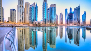 Stunning Dubai skyline at dusk featuring the Burj Khalifa and modern skyscrapers illuminated against a colorful evening sky with city lights reflecting on the water.