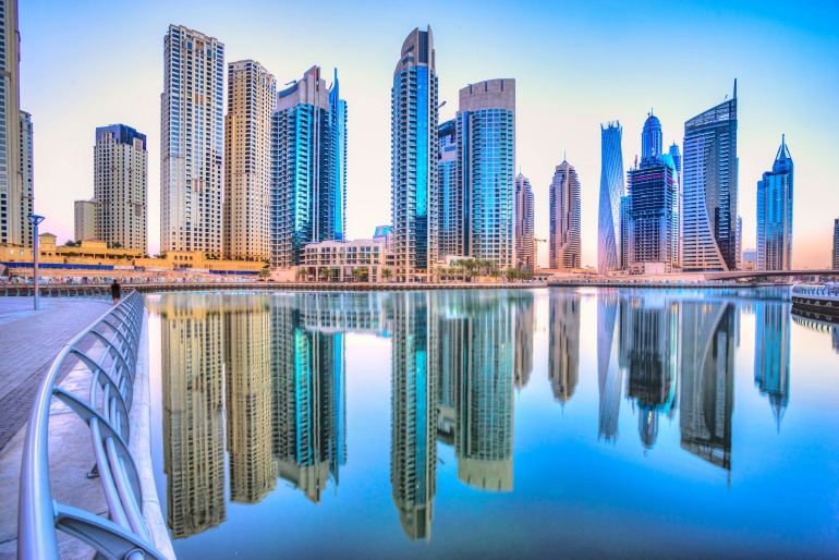 Stunning Dubai skyline at dusk featuring the Burj Khalifa and modern skyscrapers illuminated against a colorful evening sky with city lights reflecting on the water.