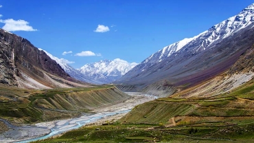 Breathtaking view of Pin Valley in Spiti, Himachal Pradesh, with rugged mountain terrain, a winding river, and clear blue skies highlighting the region’s natural beauty.