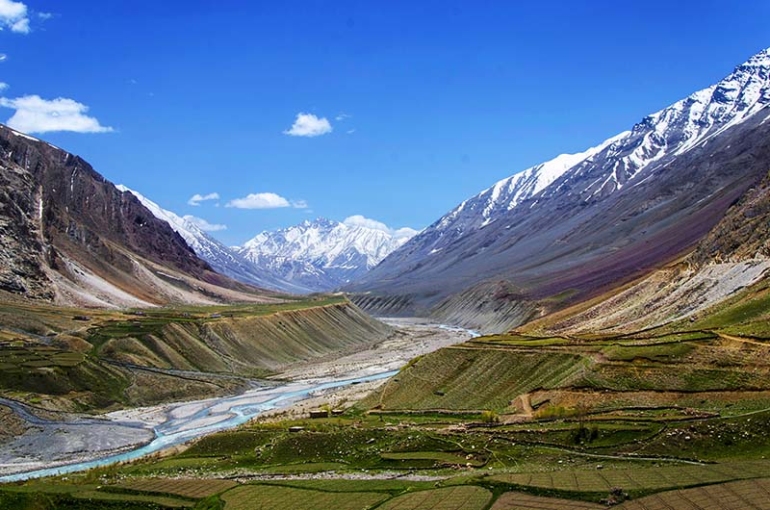 Breathtaking view of Pin Valley in Spiti, Himachal Pradesh, with rugged mountain terrain, a winding river, and clear blue skies highlighting the region’s natural beauty.