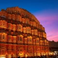The iconic Hawa Mahal in Jaipur, Rajasthan, showcasing its unique pink sandstone honeycomb façade with numerous small windows and intricate latticework under a clear sky.