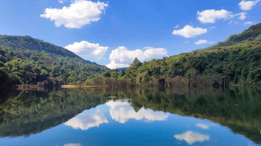 Scenic view of Chandoli forest reservoir reflecting blue sky and lush green hills