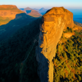 Aerial view of Harihar Fort in Maharashtra with vertical rock-cut steps and surrounding green hills during sunrise.