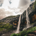 Stunning view of Kataldhar Waterfall cascading down a rocky cliff amidst lush green surroundings in Lonavala during the monsoon.