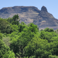Manikgad Fort view from base village surrounded by lush green forest in Sahyadri range, Raigad district