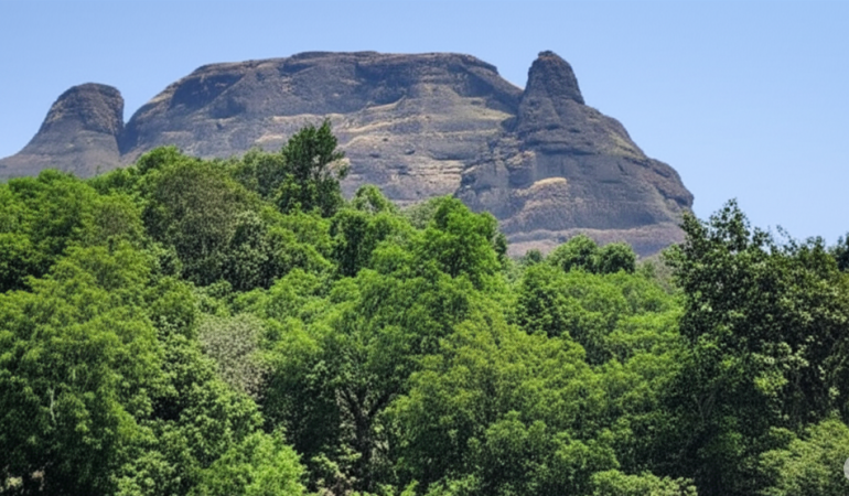 Manikgad Fort view from base village surrounded by lush green forest in Sahyadri range, Raigad district