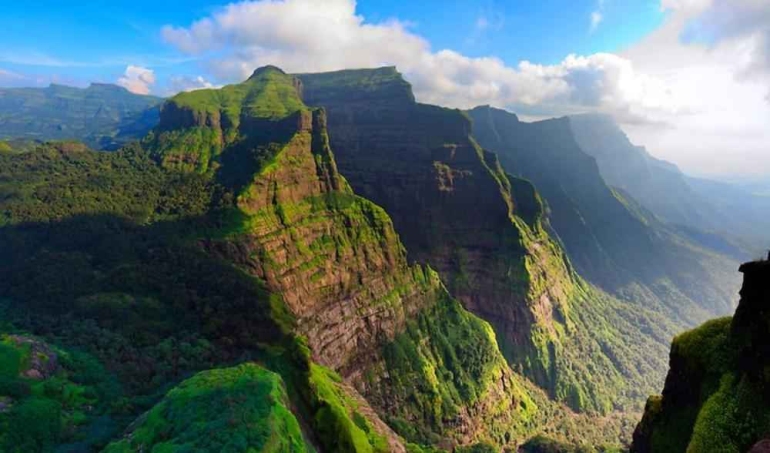 A breathtaking aerial view of Ratangad Fort covered in lush greenery, surrounded by the Sahyadri mountain range in Maharashtra.